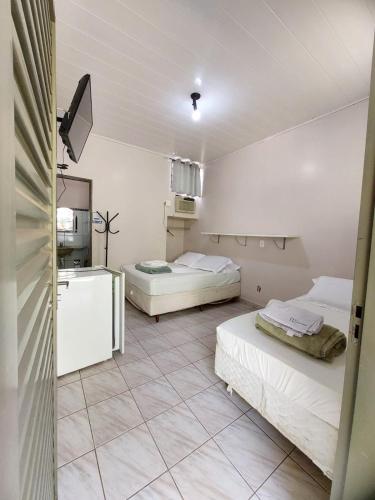 a room with two beds and a kitchen in it at Residencial Joman Goiânia in Goiânia