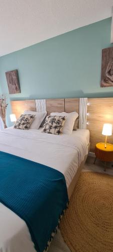 une chambre avec un grand lit avec une couverture bleue dans l'établissement Le Ptit Ecrin du Lerins, à Cannes