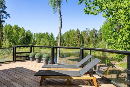 a deck with two lounge chairs on top of it at Stay North - Mustikka in Lohja