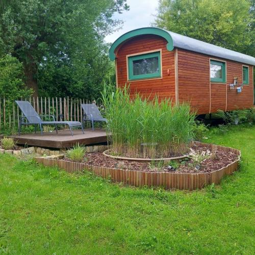 a tiny house in a yard with a bench at Roulotte Ravel-Emoi Chambre Insolite de Charme in Ramillies