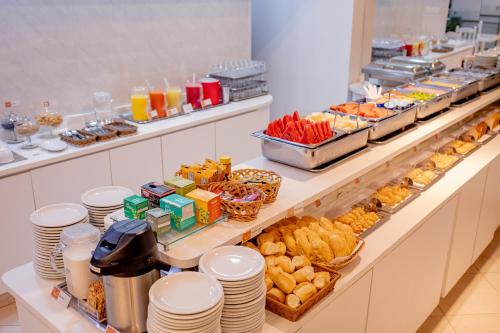 a buffet line with plates and food on it at Hotel San Gabriel in Sao Paulo