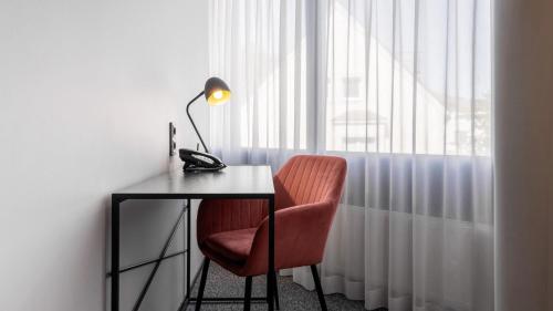 a desk with a lamp and a chair next to a window at Fonnental Design Hotel Tallinn in Tallinn