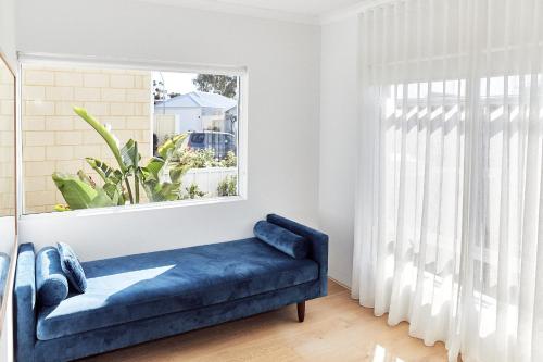 a blue couch in a room with a window at The Elanora in Dunsborough