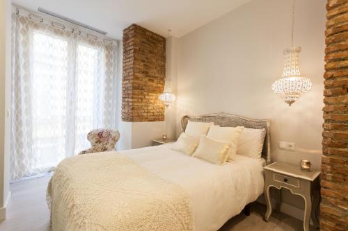 a bedroom with a white bed and a chair at Graffiti Suites Málaga in Málaga