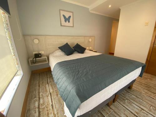 a bedroom with a large bed with blue pillows at Hotel Mareblu Iquique in Iquique