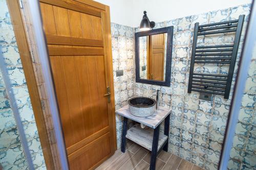 a bathroom with a sink and a wooden door at Nostos Country House in Tsagarada