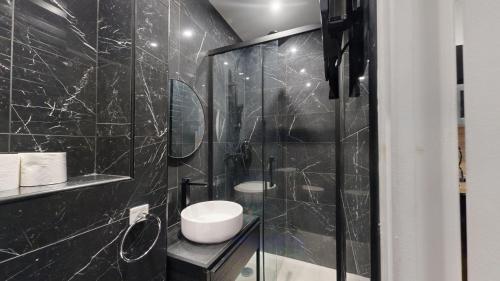 La salle de bains est pourvue de carrelage noir, de toilettes et d'une douche. dans l'établissement 195 Suite Royal - Superb apartment in Paris, à Paris