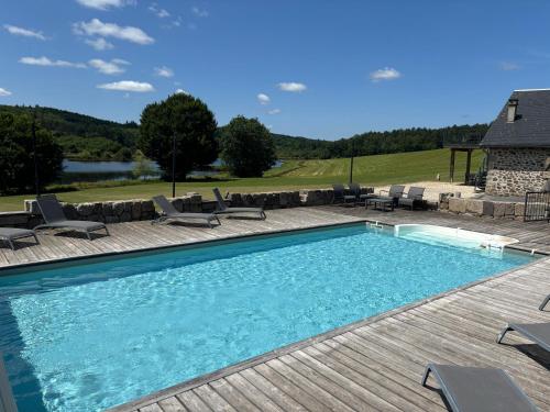 a large swimming pool with chairs and a table at Domaine des Annouillards in Sornac