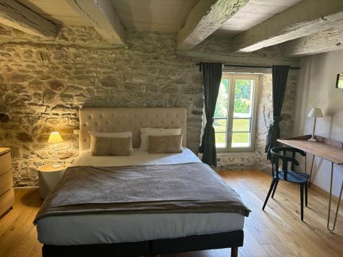 a bedroom with a bed and a stone wall at Domaine des Annouillards in Sornac