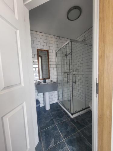 a bathroom with a glass shower and a sink at The Boat House Waterside Home in Adrigole
