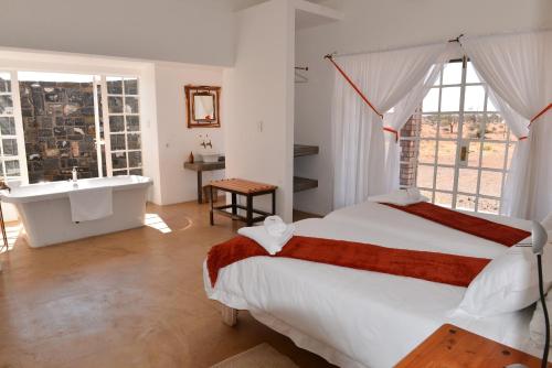 a bedroom with a bed and a tub and a sink at Alte Kalkoefen Lodge in Simplon