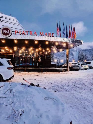 a snow covered building with cars parked in front of it at Hotel Piatra Mare in Poiana Brasov