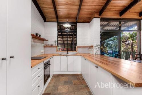 une cuisine avec des armoires blanches et un comptoir en bois dans l'établissement Historical cottage in the hills, à Greenmount