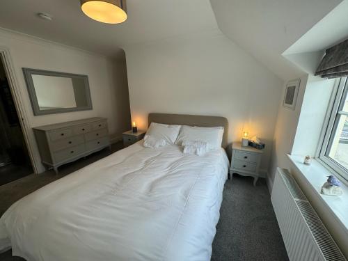 a bedroom with a large white bed with two night stands at Wisteria House 3 bed sleeps 6 in Camelford