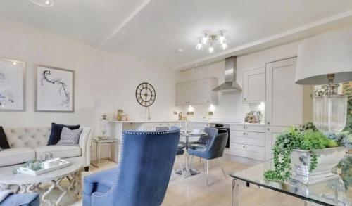 a kitchen and living room with blue chairs and a table at The Wellington Suite, Garrick House in Lichfield