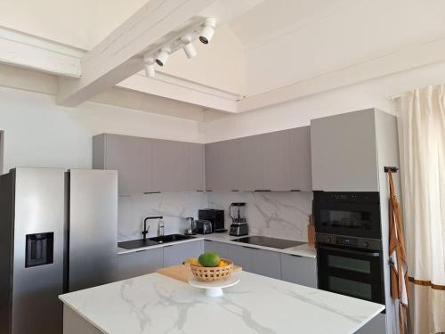 - une cuisine blanche avec un bol de fruits sur un comptoir dans l'établissement Grande maison élégante, à Argenteuil