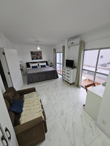a bedroom with a bed and a couch and a television at Suíte en apartamento privado in Balneário Camboriú