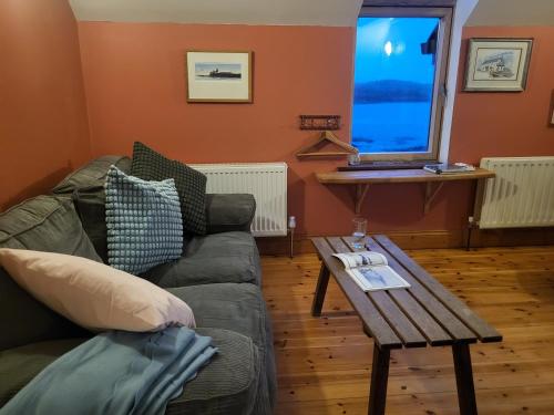 a living room with a couch and a table with a laptop at The Boat House Waterside Home in Adrigole