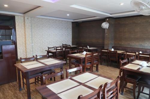 a dining room with wooden tables and chairs at Hotel Embassy in Dibrugarh