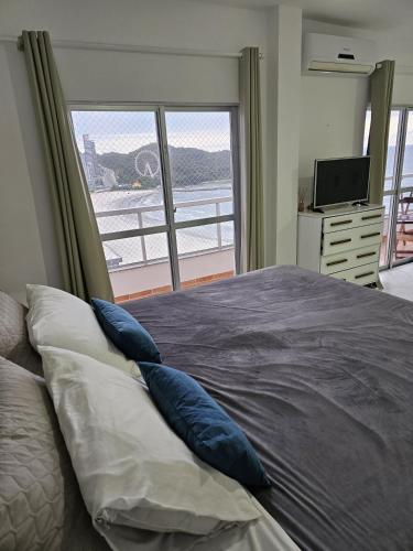 a bedroom with a large bed with blue pillows at Suíte en apartamento privado in Balneário Camboriú