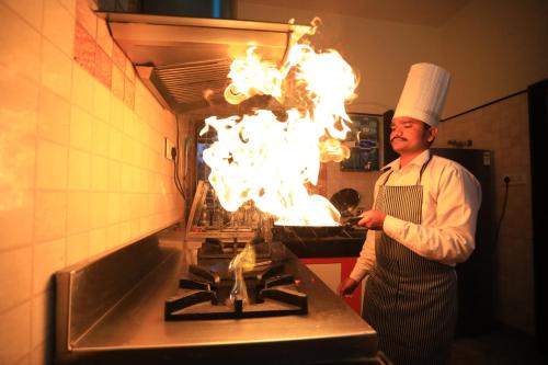 a chef is standing in a kitchen with fire on the stove at Harnawa Haveli - A Boutique Heritage Stay in Jaipur