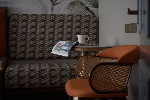 a table and chair with a newspaper and a cup of coffee at Renjoy Hotel -Xiamen Zhongshan Road Pedestrian Street in Xiamen