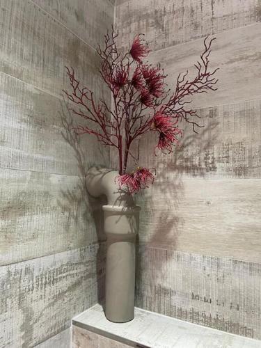 un vase avec des fleurs rouges sur un mur dans l'établissement À louer beau deux-pièces St-Etienne-de-Tinée, à Saint-Étienne-de-Tinée