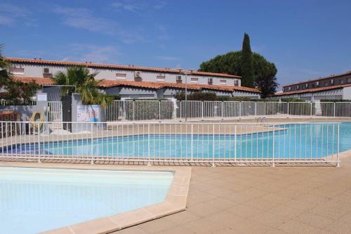 une grande piscine entourée d'une clôture. dans l'établissement Beau T3 avec piscine collective proche Port,plage et commerces-4JDN822, à Saint Cyprien Plage