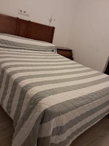 a bed with a striped comforter in a bedroom at Hostal Lizana 2 in Huesca
