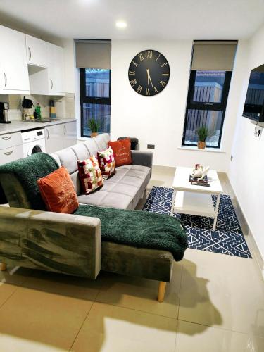 a living room with a couch and a clock on the wall at Luxurious 3 bed Ensuites & kitchenettes Nr LGI Hospital & Uni - Free 5G WIFI & Netflix Short Stays - Contractors Free Parking in Leeds