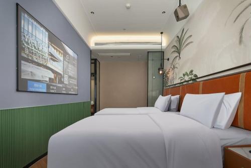 a bedroom with two white beds and a tv at Renjoy Hotel -Xiamen Zhongshan Road Pedestrian Street in Xiamen