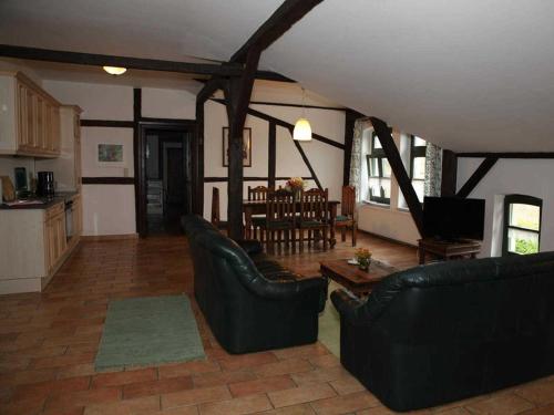 a living room with black leather furniture and a kitchen at Ferienwohnungen im Bauernhaus _ Ob in Papendorf