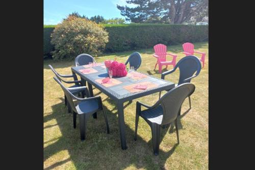 a table with chairs and a table with flowers on it at Villa pour 6 pers - vue mer - 5 min d'un site magnifique - Lanmodez - Paimpol, Côtes d'Armor, Bretagne in Lanmodez