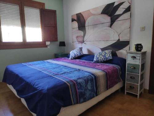 a bedroom with a bed with a large painting on the wall at Florida Sol adorable adosado con Piscina in Denia