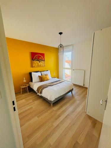 une chambre avec un lit avec un mur jaune dans l'établissement Lascano Parking GRATUIT proche Gare Aéroport Eurexpo GROUPAMA STADIUM, à Villeurbanne