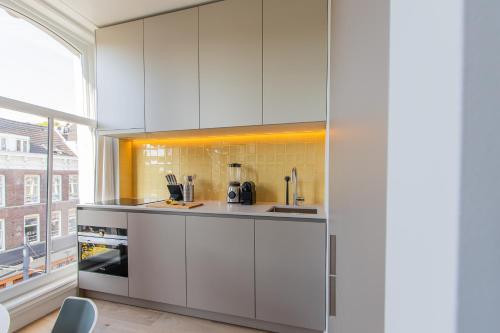 a kitchen with white cabinets and a large window at OHotellMe City Apartments Rotterdam in Rotterdam
