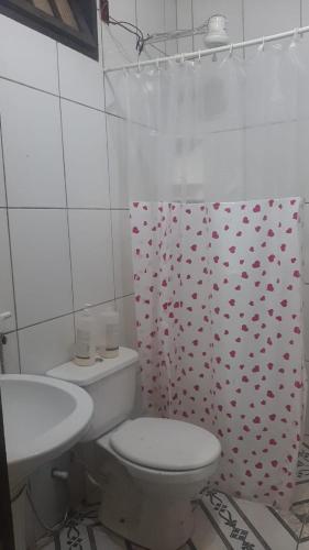 a bathroom with a toilet and a shower curtain with hearts at Casa Marataízes in Marataizes