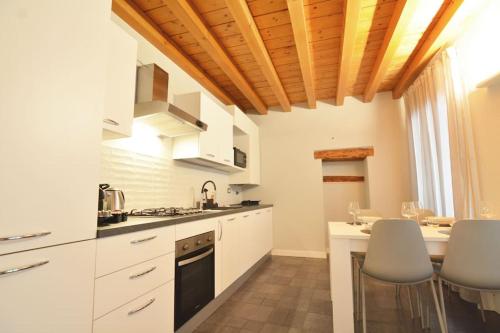 a kitchen with white cabinets and a table with chairs at Dimora Leon Bianco - eleganza e centralità in Padova