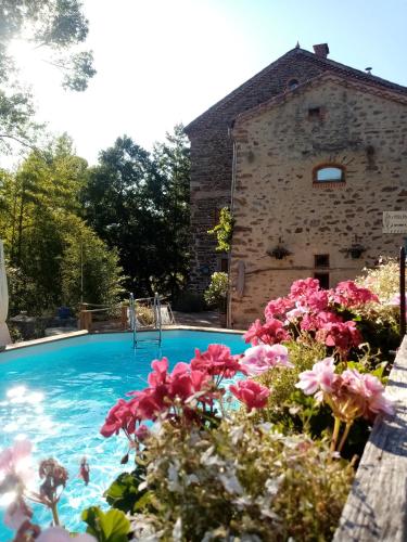 une piscine avec des fleurs devant un bâtiment dans l'établissement Moulin du Bateau - Gîte de Charme - Piscine - Nature, à Léotoing