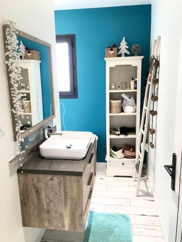 La salle de bains est pourvue d'un lavabo et d'un mur bleu. dans l'établissement Villa avec piscine entre terre et mer, à Saint-Hilaire-de-Brethmas