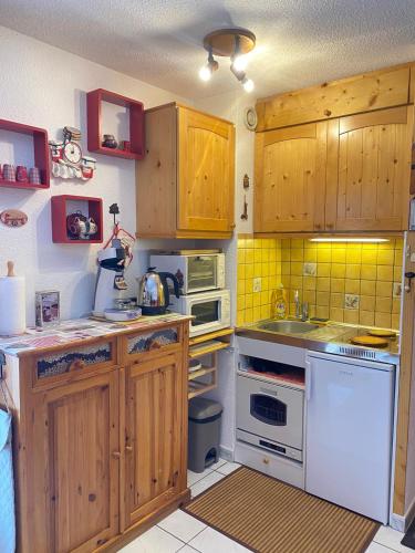- une cuisine avec des placards en bois et des appareils blancs dans l'établissement Studio, à Arâches-la-Frasse