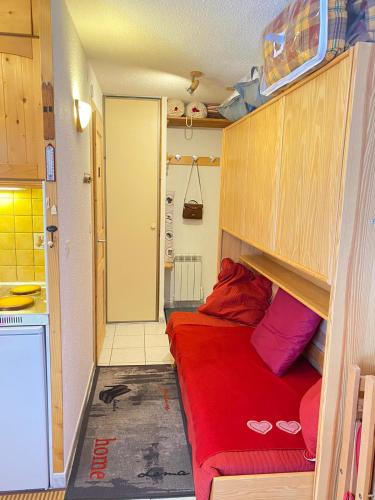 une petite chambre avec un lit rouge dans une cuisine dans l'établissement Studio, à Arâches-la-Frasse