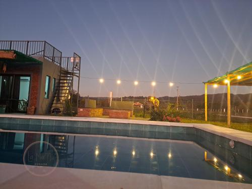 una piscina frente a una casa por la noche en Posada LA MARRU, en Paraguarí