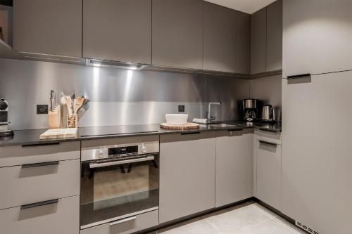 une cuisine avec des armoires blanches et des appareils en acier inoxydable dans l'établissement Cristal Des Alpes - Superb T3 - Vue Mont-Blanc, aux Houches