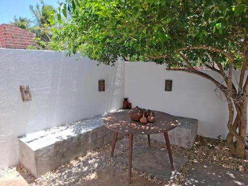 a table sitting next to a white wall with a tree at Casa Barrinha in Acaraú
