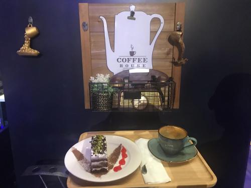 a table with a plate of cake and a cup of coffee at National Park Hotel in Baljurashi