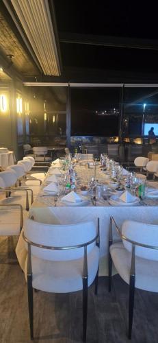 a long table with white tables and white chairs at National Park Hotel in Baljurashi