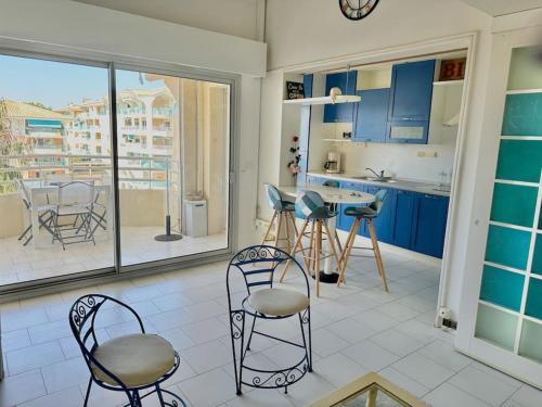 une cuisine avec des placards bleus, des chaises et une table dans l'établissement Oreeduloup - Calypso T3 vue mer, à Fréjus