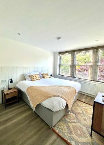a bedroom with a large bed and two windows at Mode Cottage in Lytham St Annes