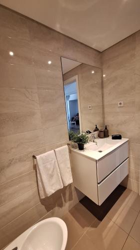 a bathroom with a sink and a toilet and a mirror at Apartamentos Jardim do Morro in Vila Nova de Gaia